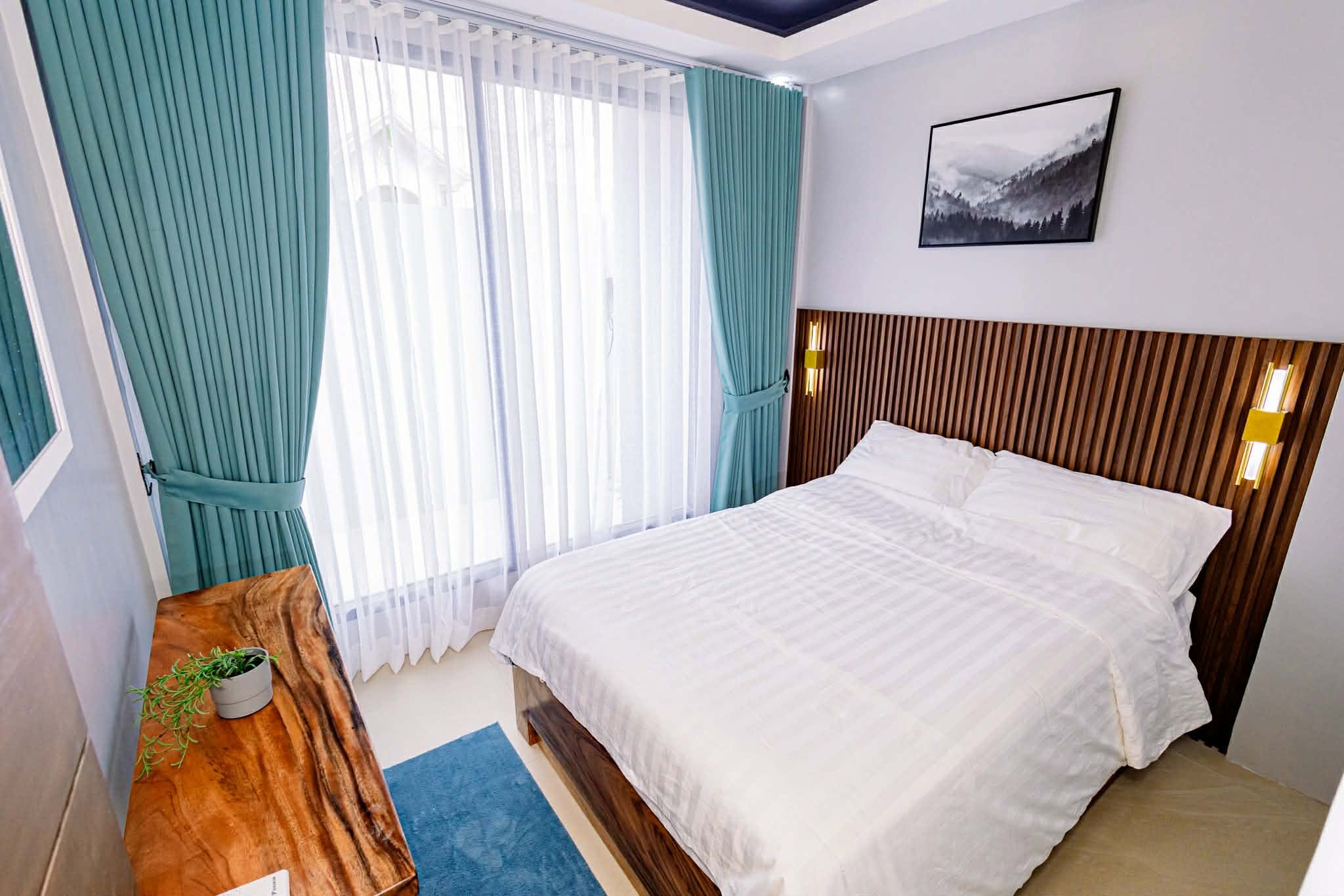 Bedroom suite with white bed, teal curtains, and wood headboard